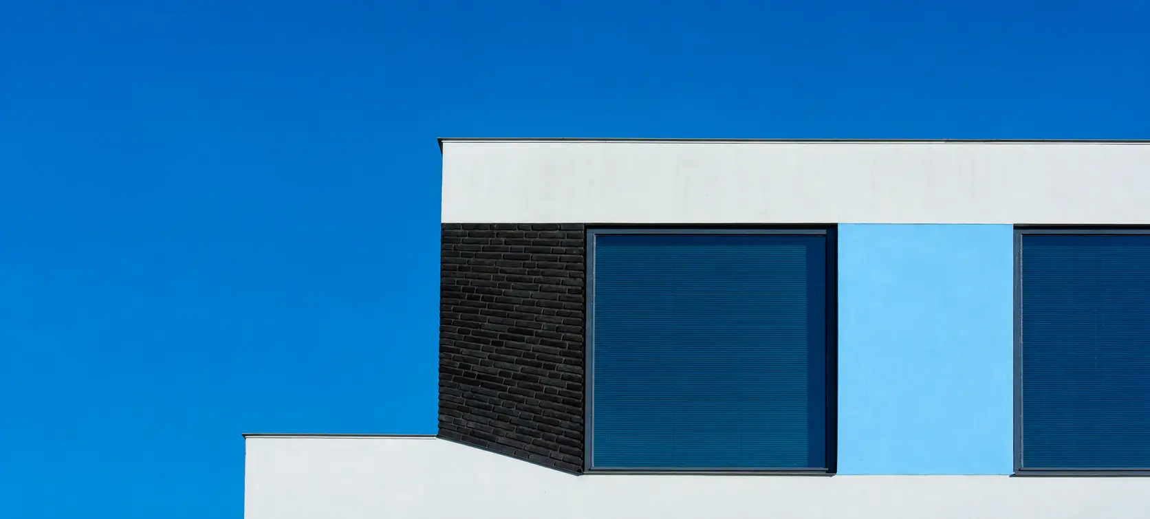 Geometric blue-and-white modern building facade under a vivid blue sky